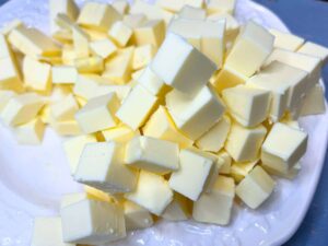 There is a white plate with cubed butter.