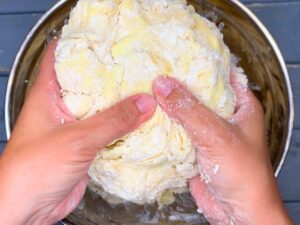 A woman clumping pie dough together.