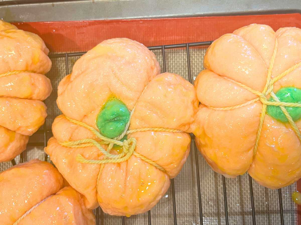 Unbaked pumpkin bagels on a wire rack.