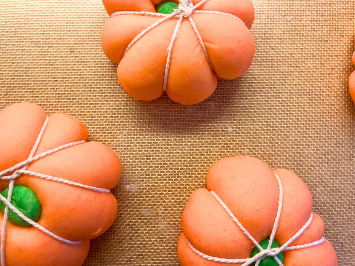 Risen orange bagel dough wrapped in kitchen twine.