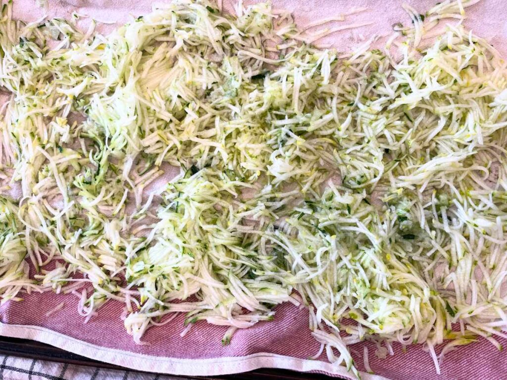 There are shreds of zucchini on a kitchen towl.