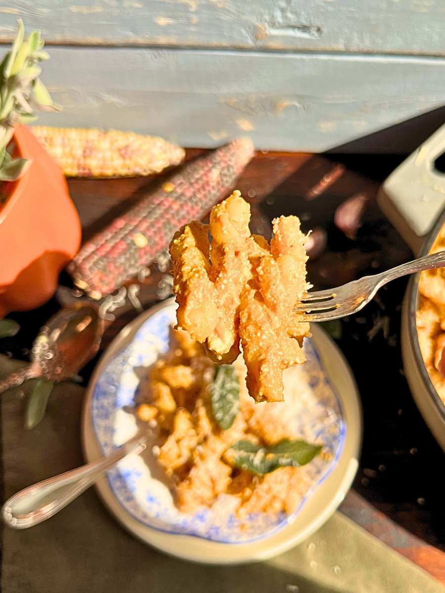 There is a woman holding a forkful of pumpkin and sage pasta.