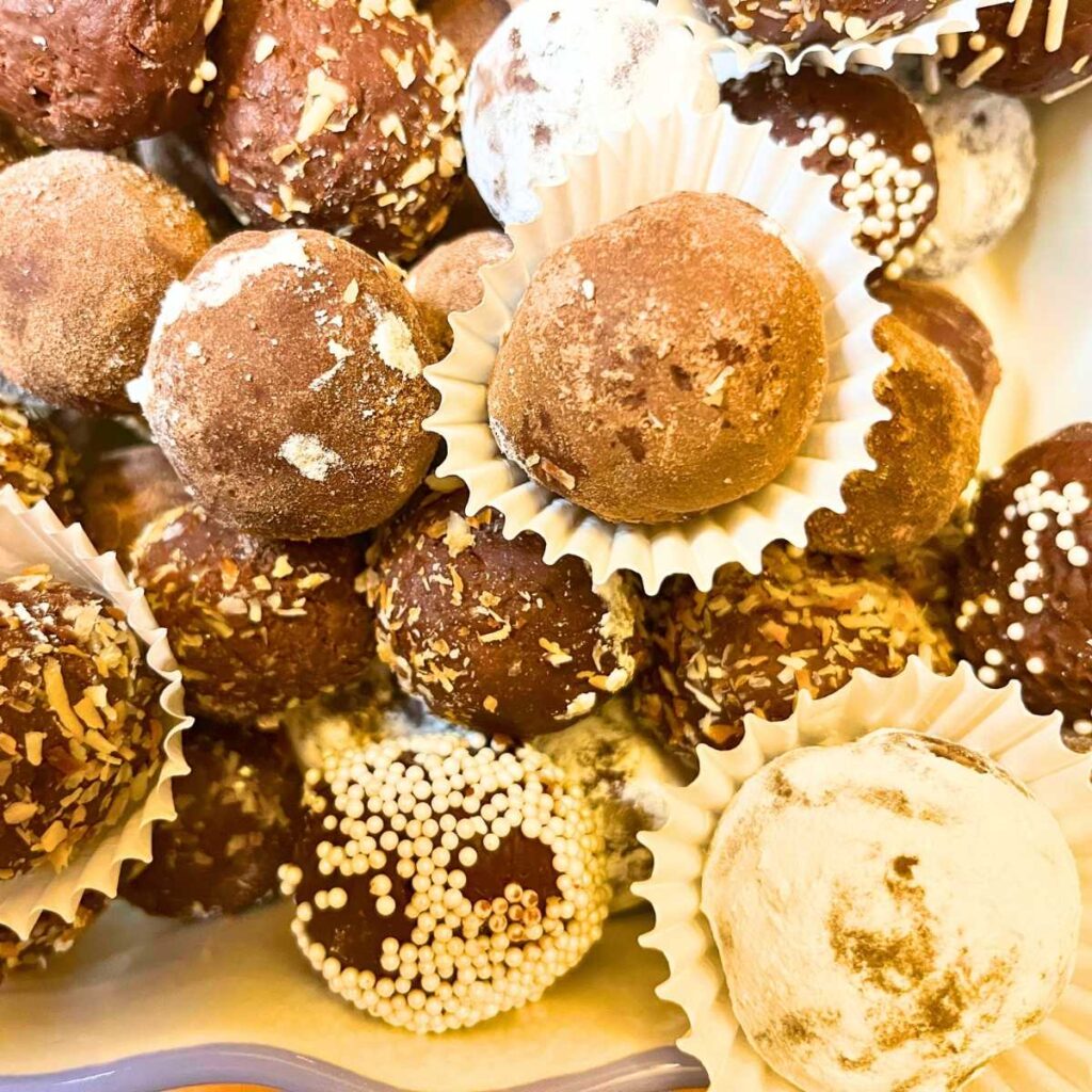 A group of chocolate truffles with different coatings in a dish. There are some in mini muffin cups.