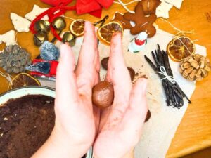 A woman is rolling chocolate into a ball between her hands.