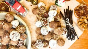 An arrangement of chocolate truffles on a piece of parchment paper. There are some in a metal pie plate to the side.