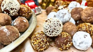 A variety of coated chocolate truffles on a piece of parchment paper. 