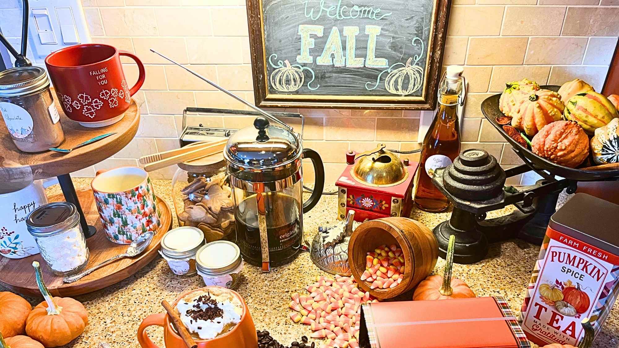 A fall themed hot drink station with coffee, tea, and hot chocolate accessories.