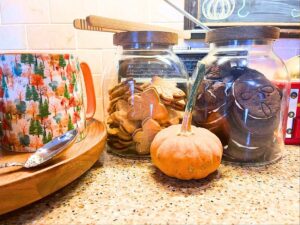 A fall coffee bar with two jars of cookies and mini pumpkins.