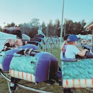 Kids riding on a dragon rollercoaster at a fair.