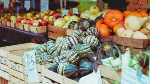 Different varieties of squash and produce for sale at a farmers market.