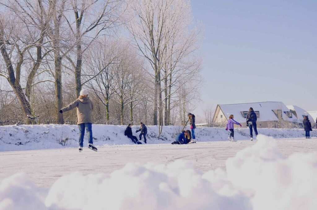 There are people skating at an out door skating rink in the winter.