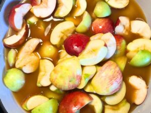 A pot full of chopped apples and apple cider.