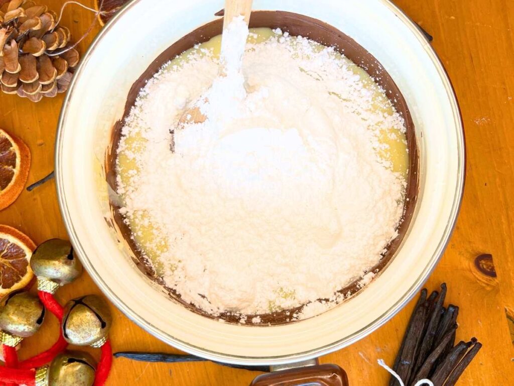 Powdered sugar inside of a white pot. There is chocolate under.