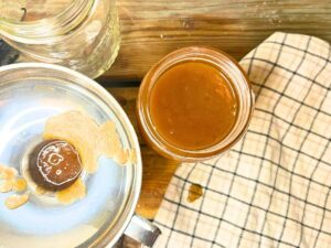 A woman is pouring apple butter through a funnel into canning jars.