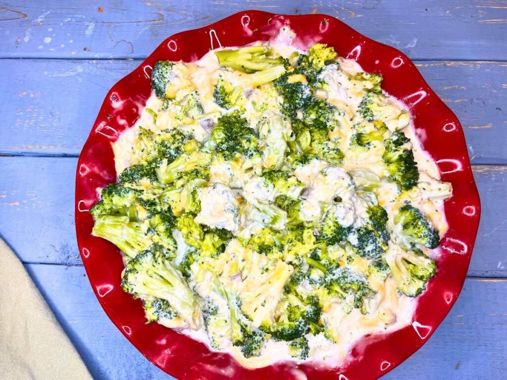 There is a creamy broccoli mixture in a red casserole dish.