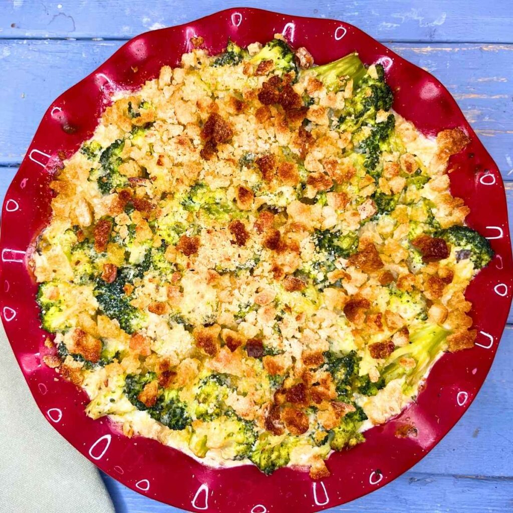 A broccoli casserole with bread crumb top in a red dish.