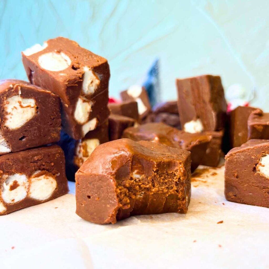 There is a piece of chocolate marshmallow fudge with a bite out of it. There are more squares behind.