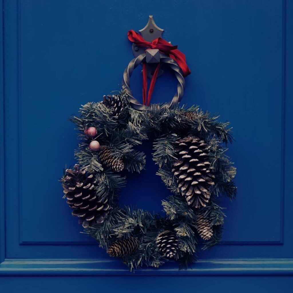 A Christmas wreath hanging on a blue door.