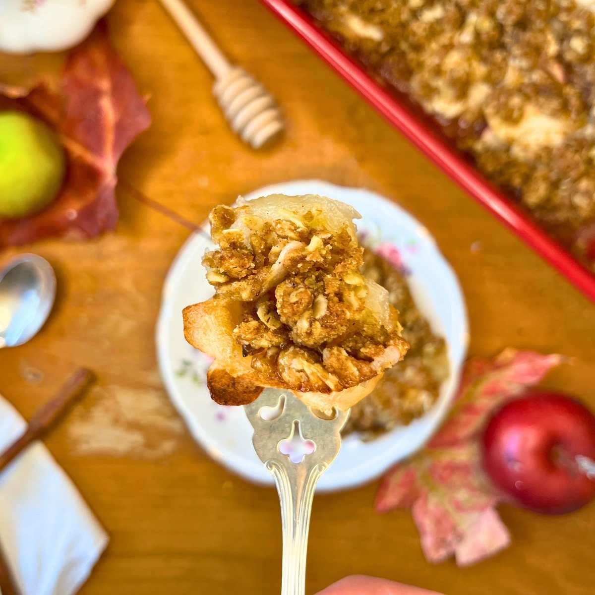 A woman is holding up a forkful of honey apple crisp.