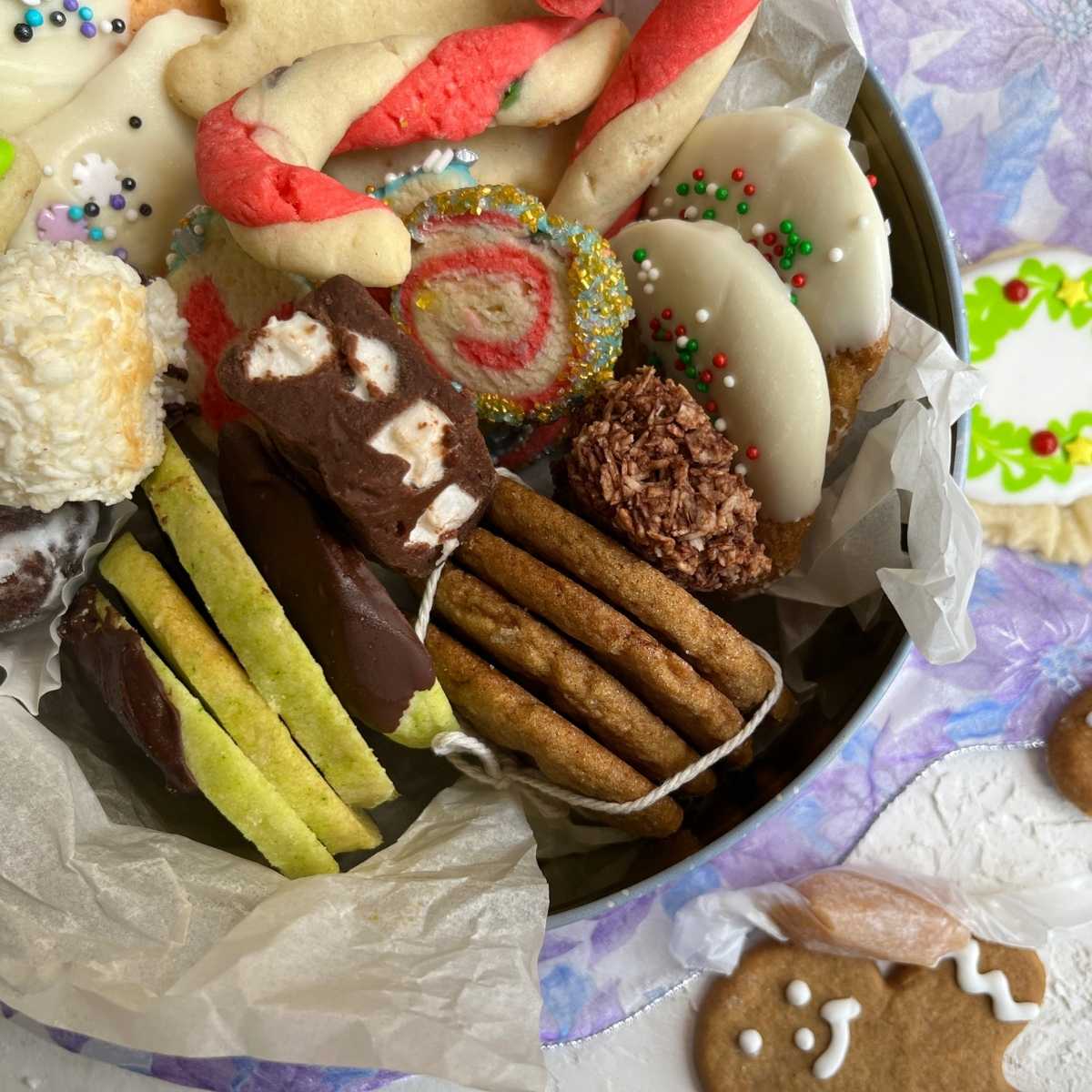 A close up look of a cookie tin packed with an assortment of Christmas cookies and treats.