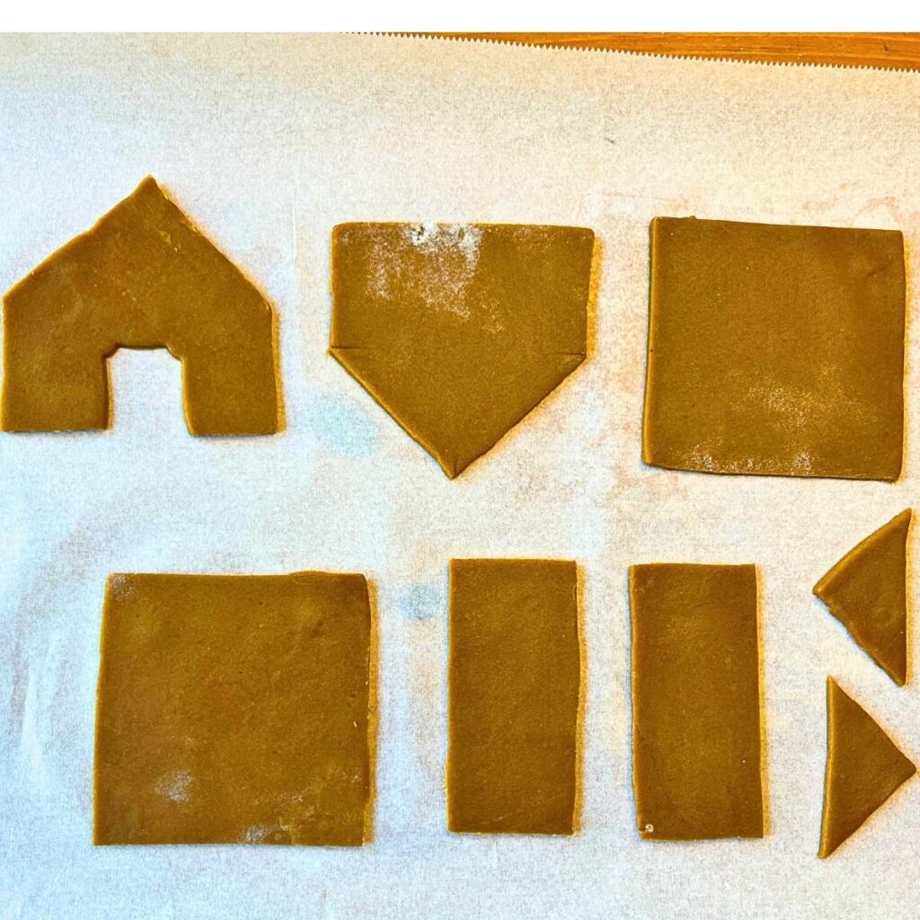 Cut out gingerbread house dough on a piece of parchment paper.