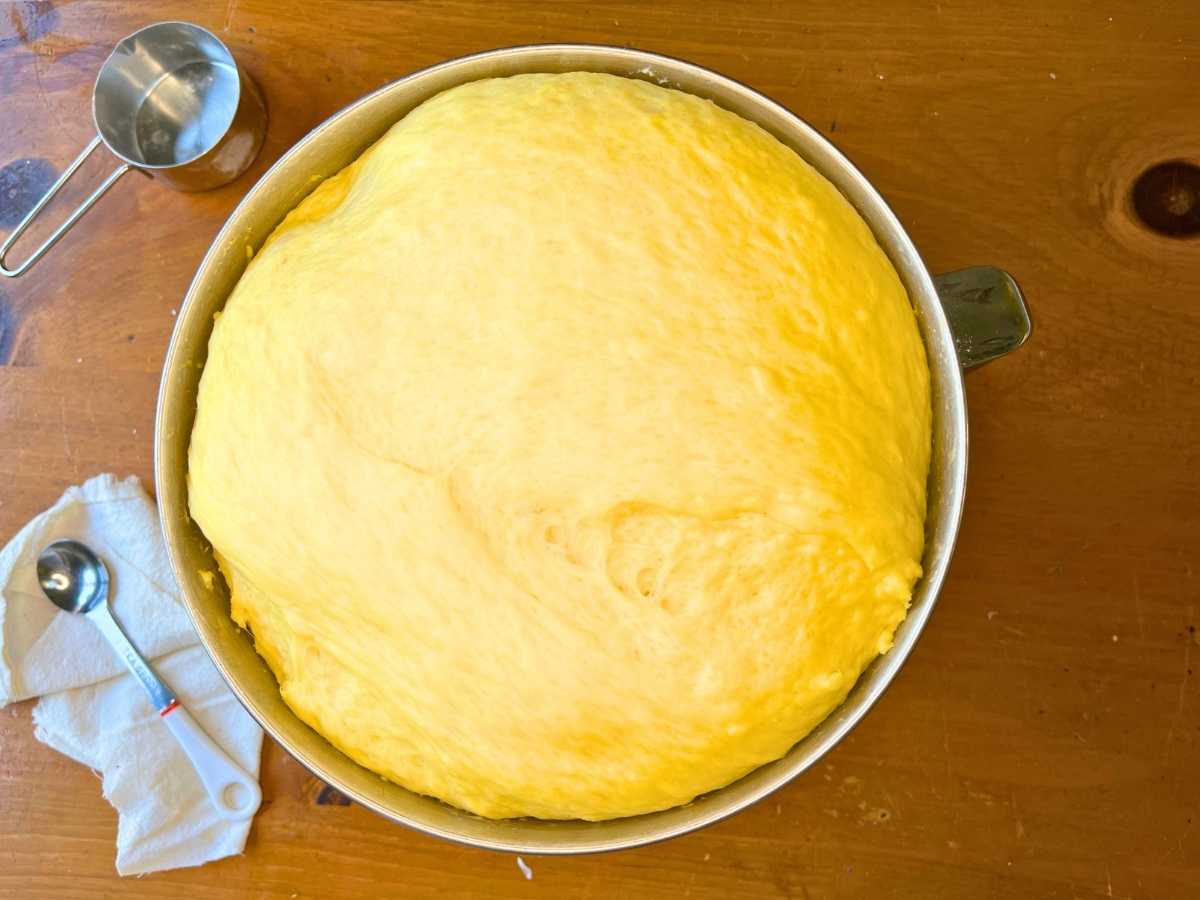 A metal bowl with risen bread dough inside.