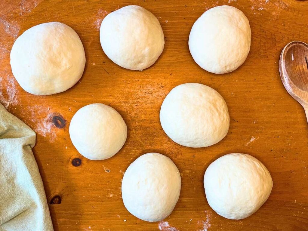 Small circles of bread dough on a wooden table.