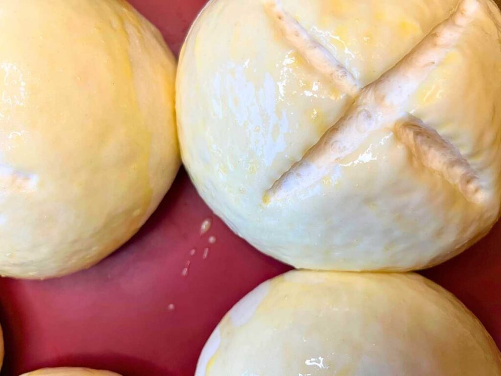 Unbaked bread bowls with egg wash brushed on top.