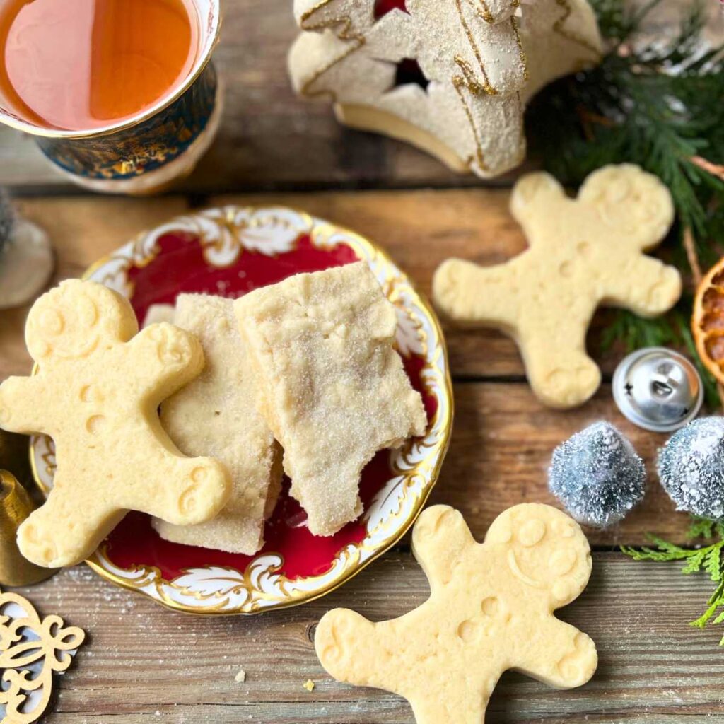 Shortbread cookies on a red plate. Some are in the shape of gingerbread men.