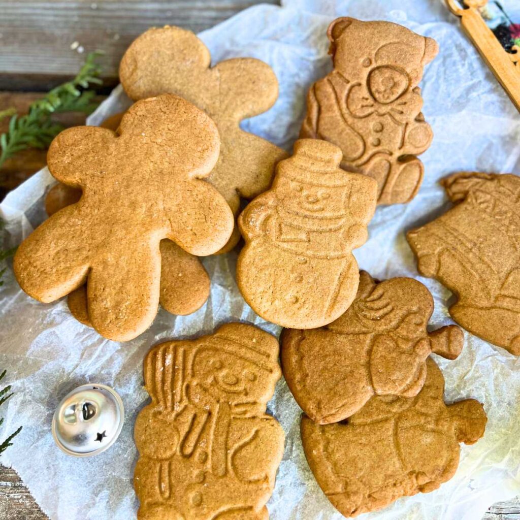 A collection of gingerbread cookie cut outs on a piece of parchment paper.