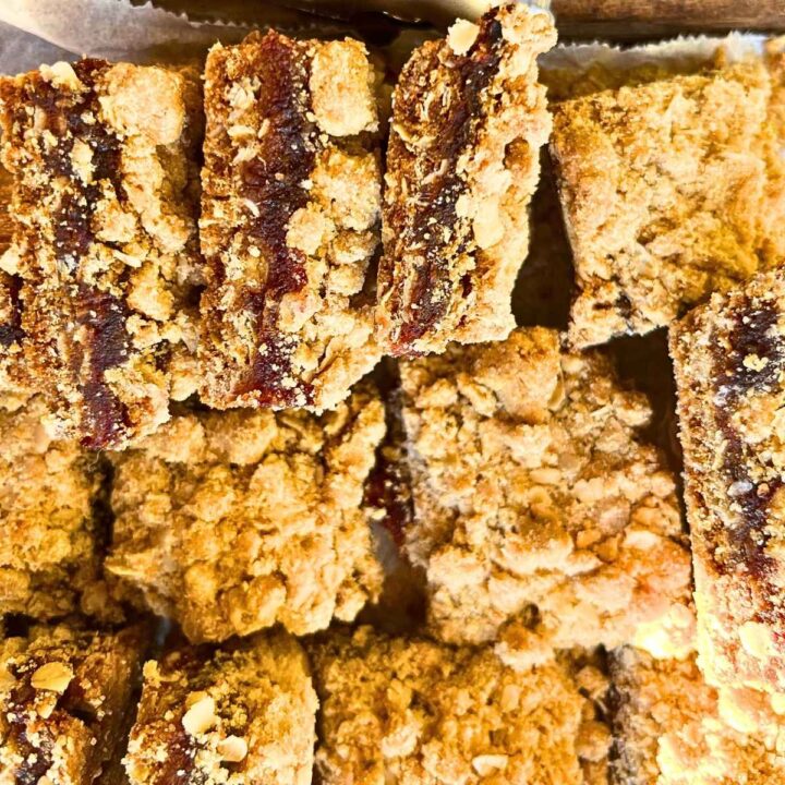 Date squares on a piece of parchment paper. Some are on their side to show the inside filling.