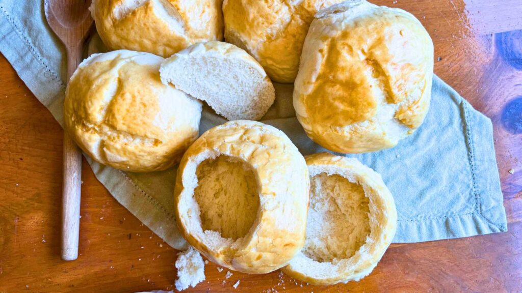 Some small round bread loaves. Some are hollowed out into bowls.