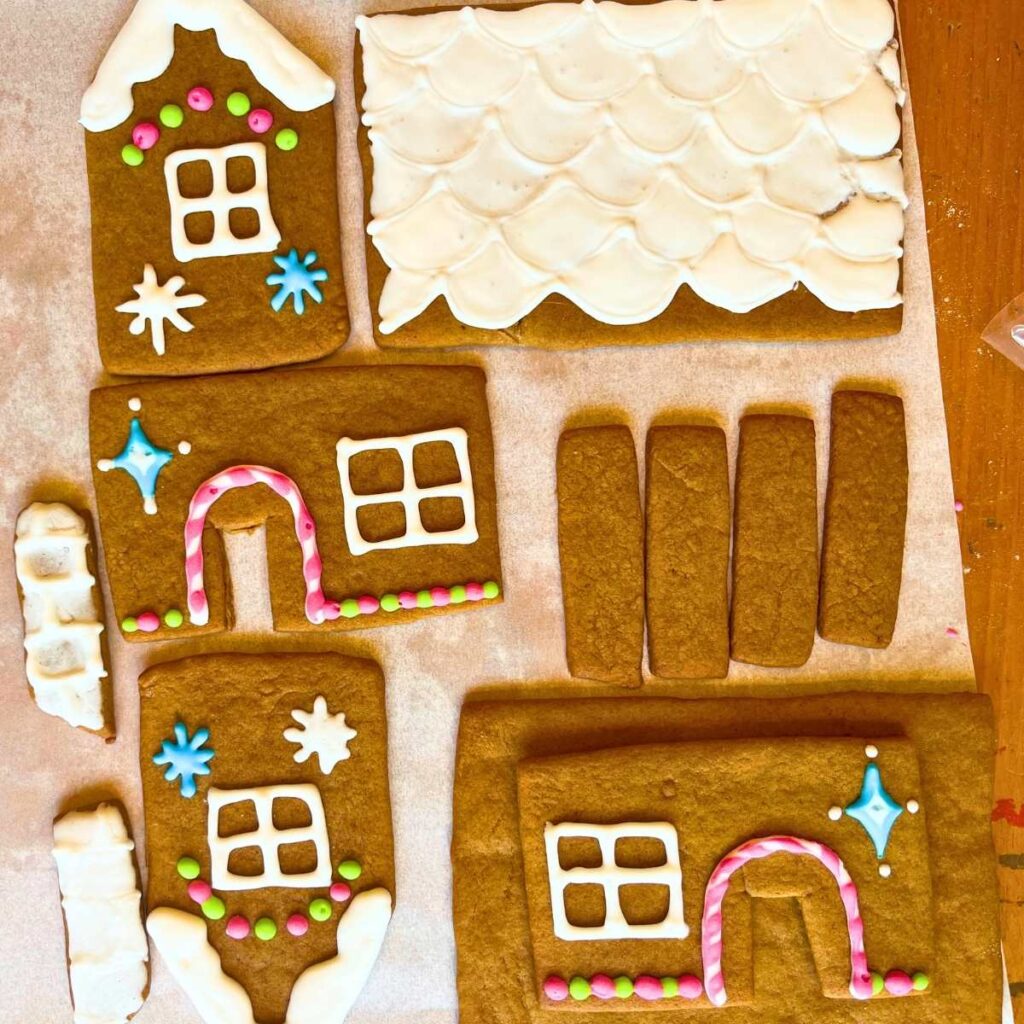 Cookies for a gingerbread house on a piece of parchment paper. they are decorated.