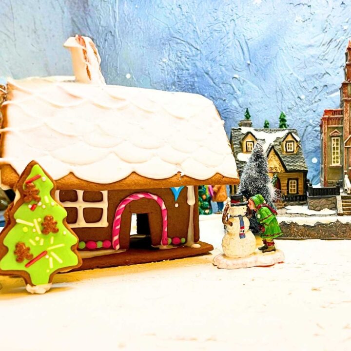 A gingerbread house decorated with royal icing. It is part of a Christmas village.