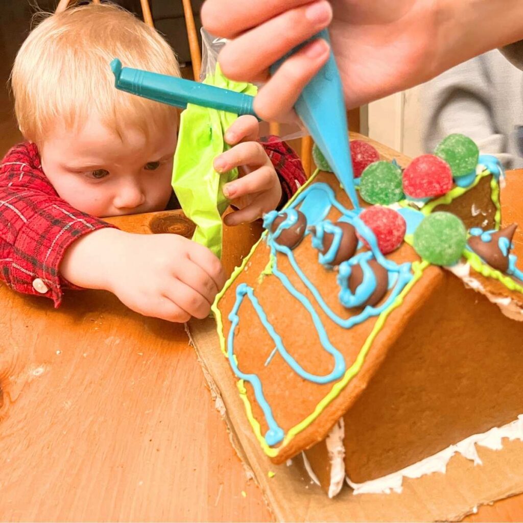 Two children decorating a gingerbread house.