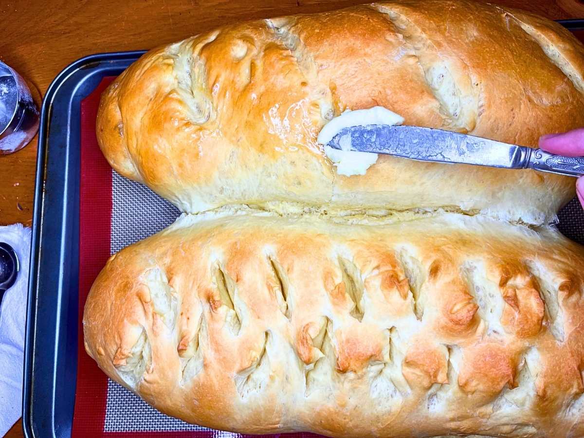 Two loaves of high protein bread that are being brushed with butter.