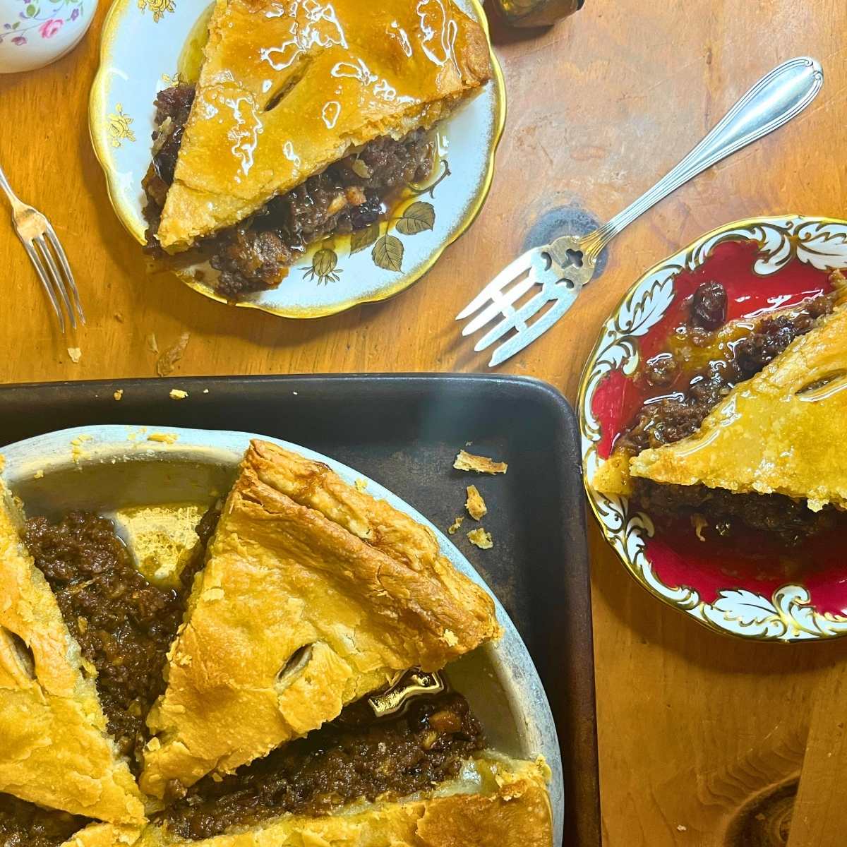 A sliced mincemeat pie. There are two plates beside with slices of pie on each.