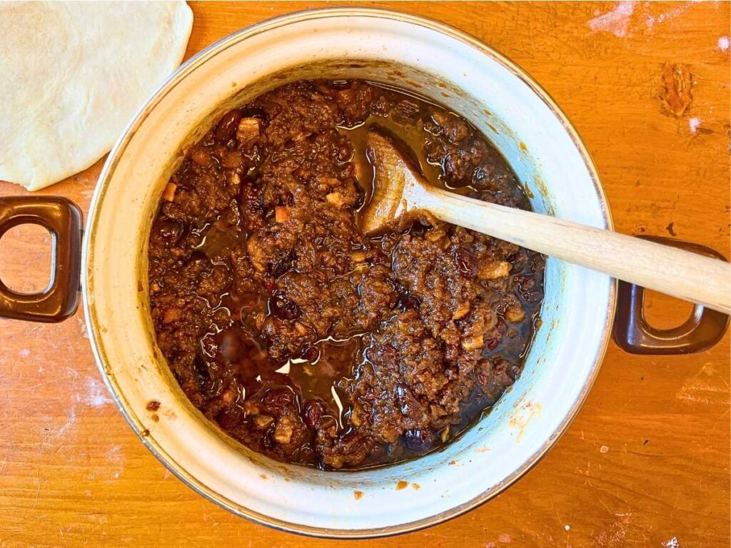 A white sauce pot with cooked mincemeat pie filing.