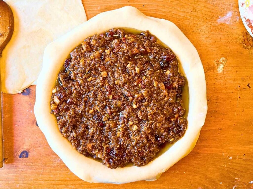 An unbaked pie shell with mincemeat pie filling inside.