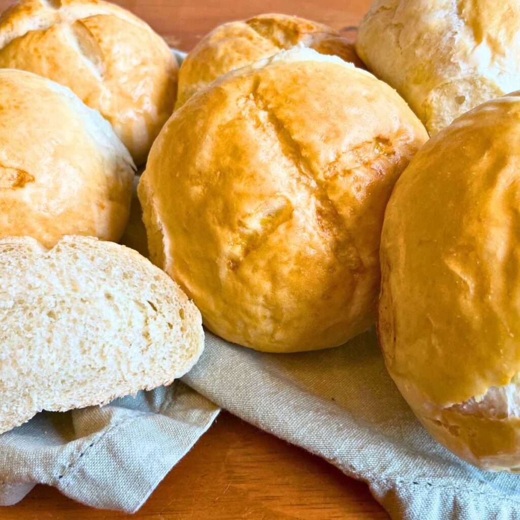 A table full of small loaves of bread. One is cut in half.