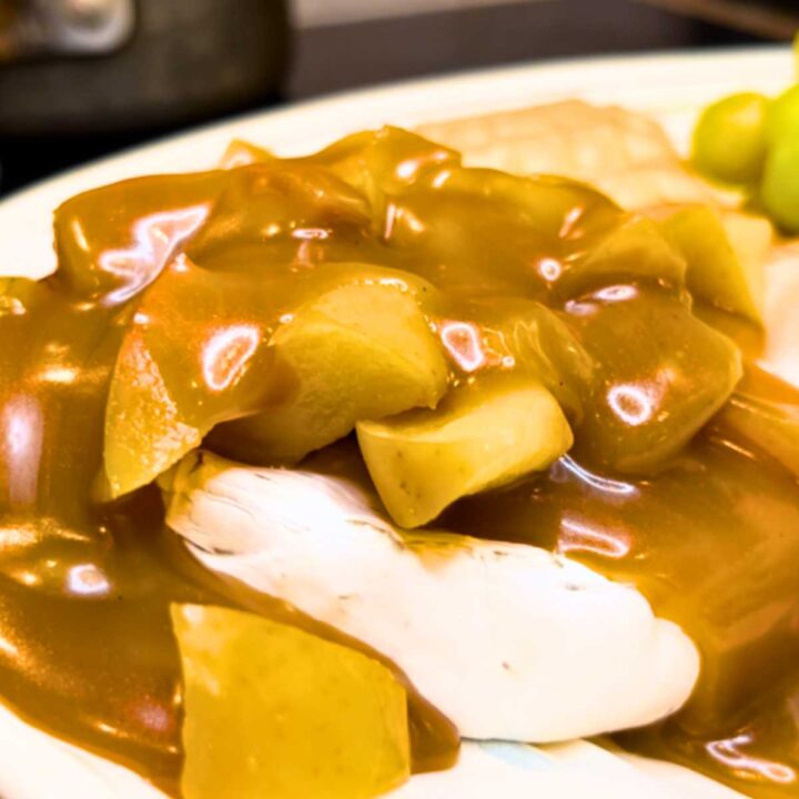 A wheel of Brie cheese covered with diced apples and caramel sauce.