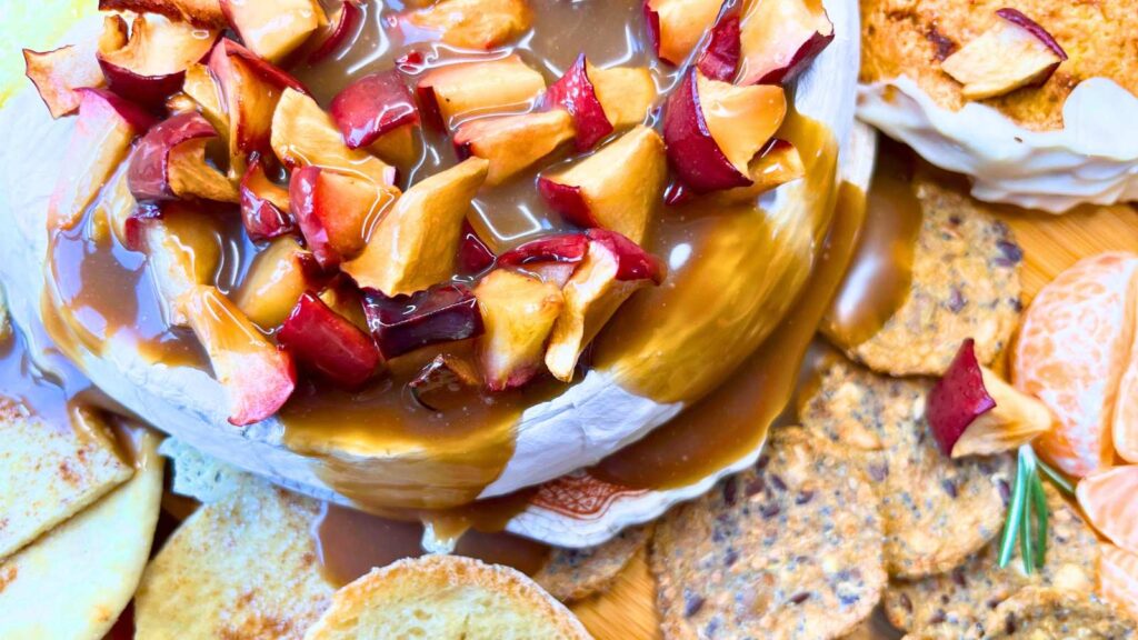 A baked Brie covered in apple pieces and caramel sauce.