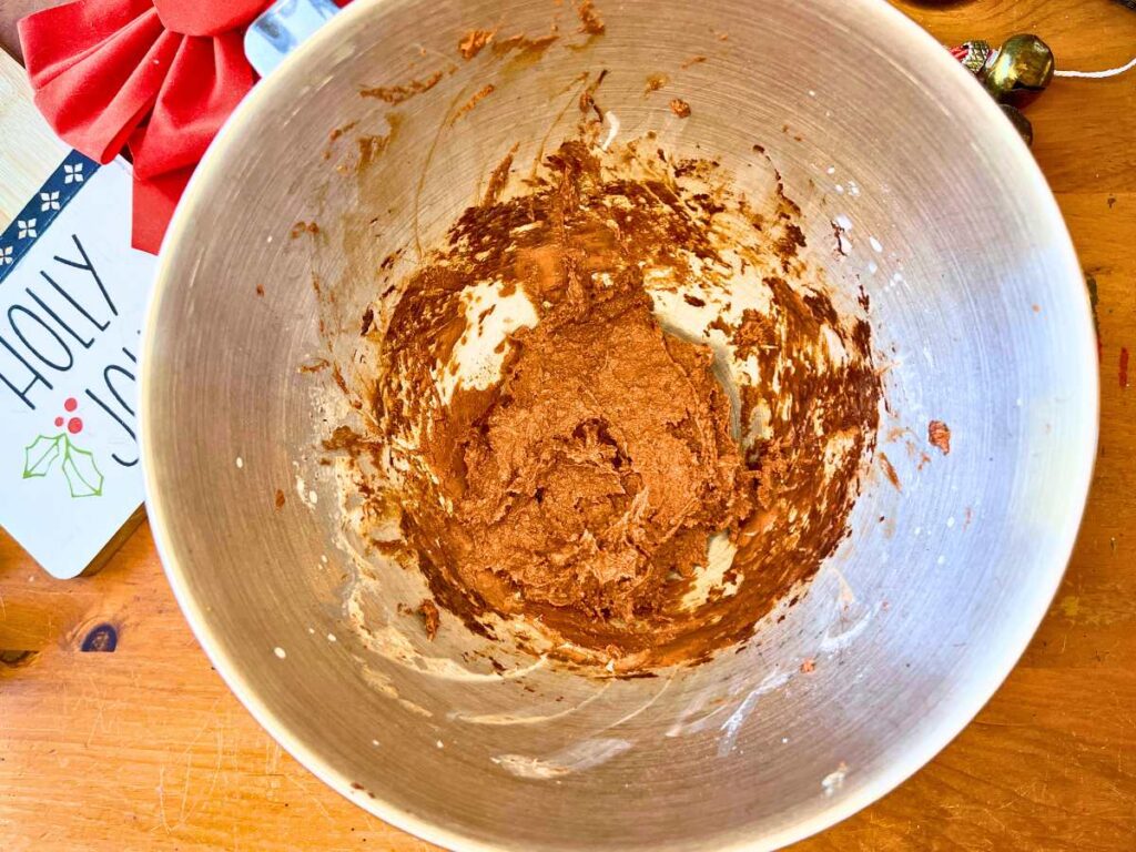 A metal bowl with chocolate icing inside.