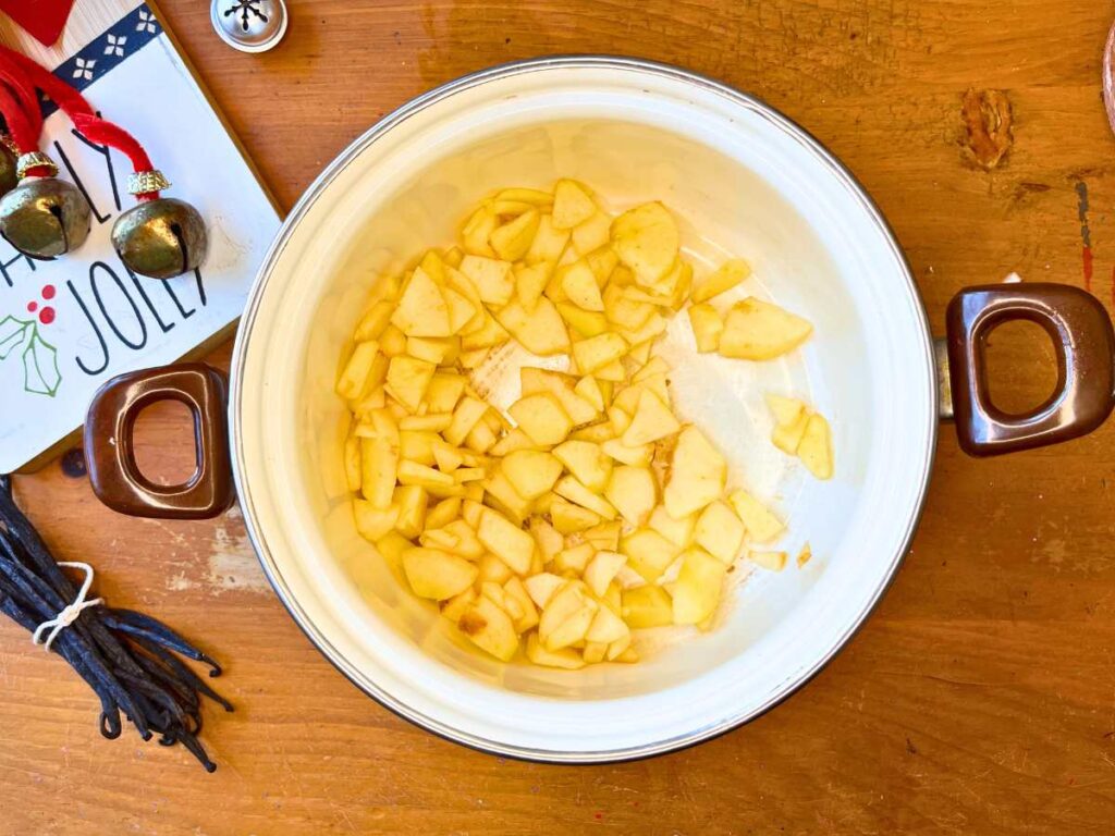 Apple pieces in a white sauce pot.