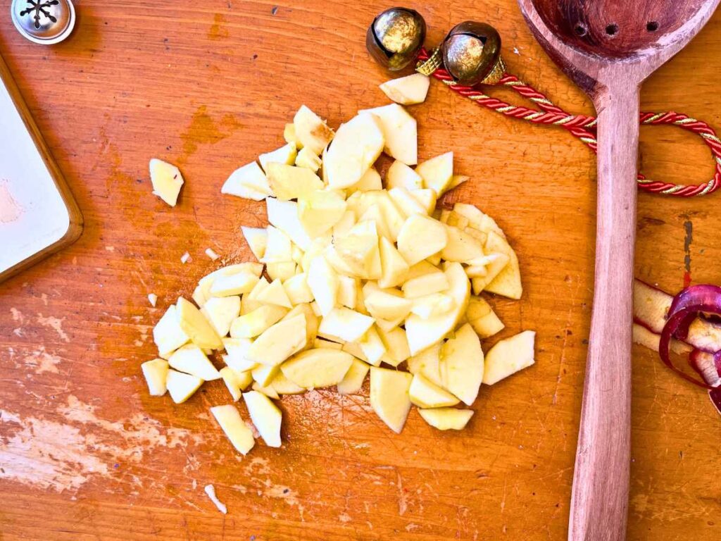 Peeled and sliced apples on a wooden table.