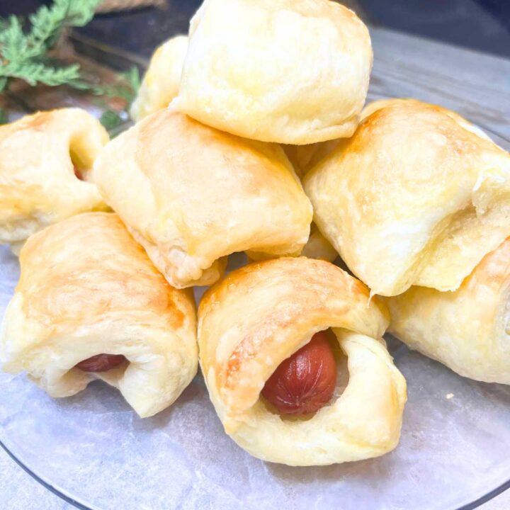 Small hotdogs wrapped in puff pastry on a glass plate.