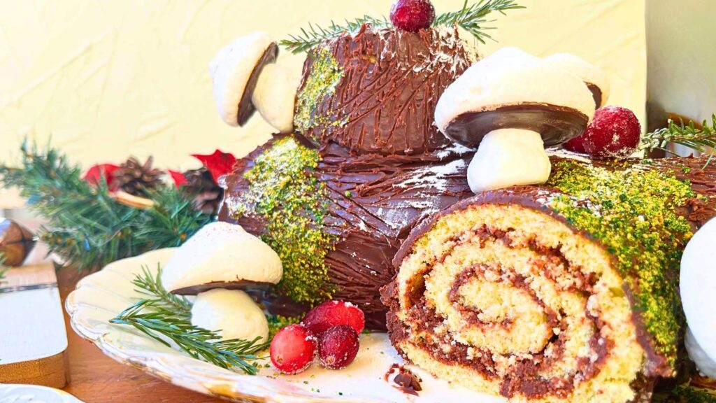 A Christmas themed chocolate cake decorated with meringue mushrooms, cranberry, and evergreen.