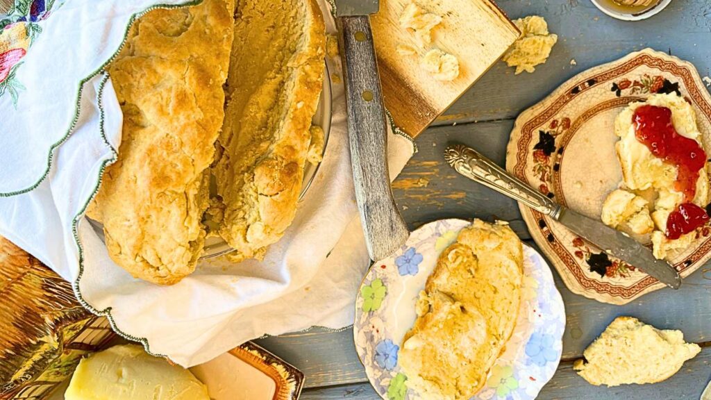 A bannock loaf sliced. There are two slices of the bread on small plates off to the side.