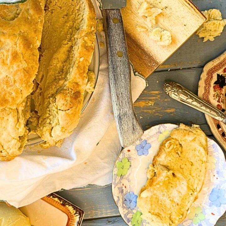 A bannock loaf sliced. There are two slices of the bread on small plates off to the side.