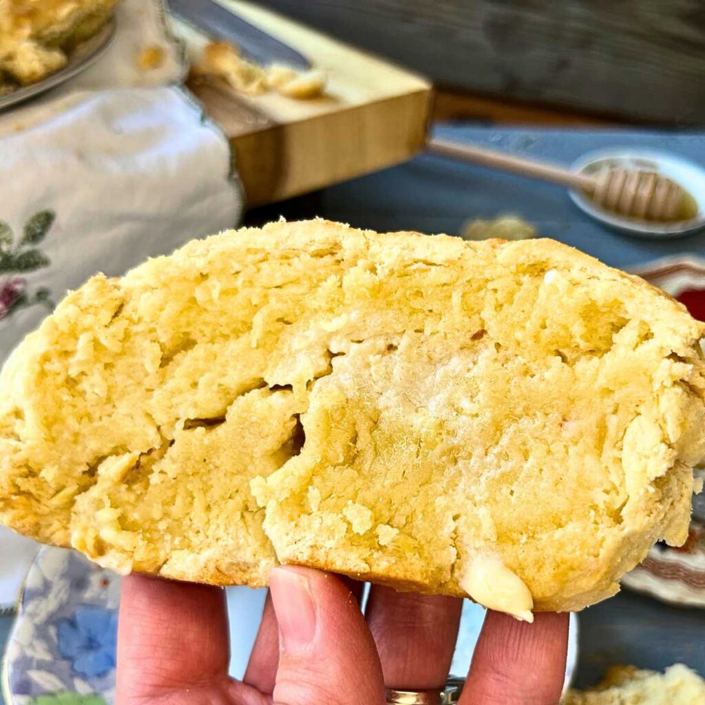 A woman is holding up a buttered slice of fresh bannock.